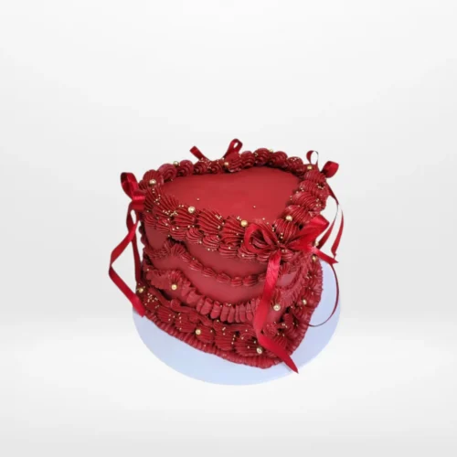 Red heart-shaped cake with smooth buttercream and personalised message.