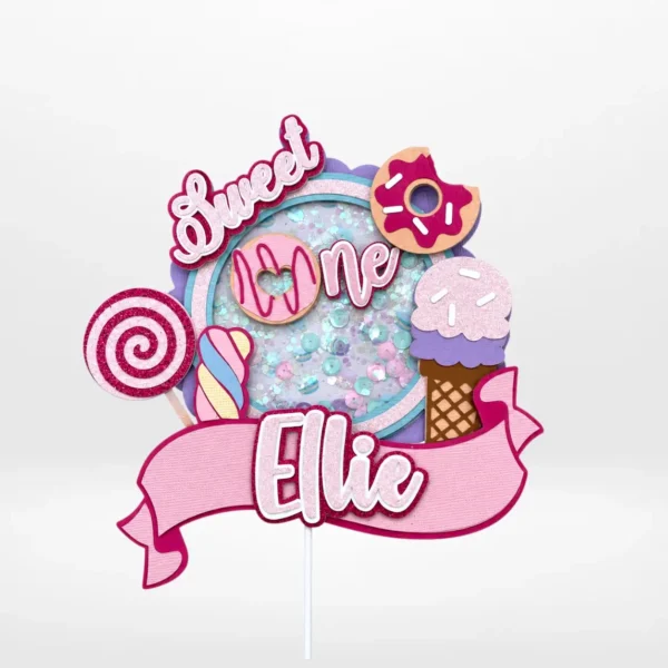 First birthday cake topper with layered 3D shaker design and sweet-themed decorations from Cake Shop Birmingham.